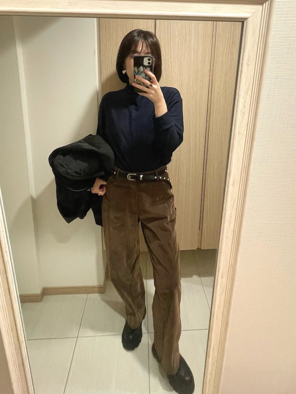 ブラック系のハンドバッグ、ブルー系のジャケット/アウター、ブラウン系のパンツを着用したレディースの冬コーディネートの2枚目の写真