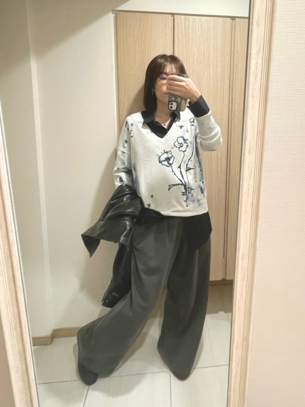 ホワイト系のニット/セーター、グレー系のスラックス、ブラック系のシャツ/ブラウスを着用したレディースの秋コーディネートの2枚目の写真