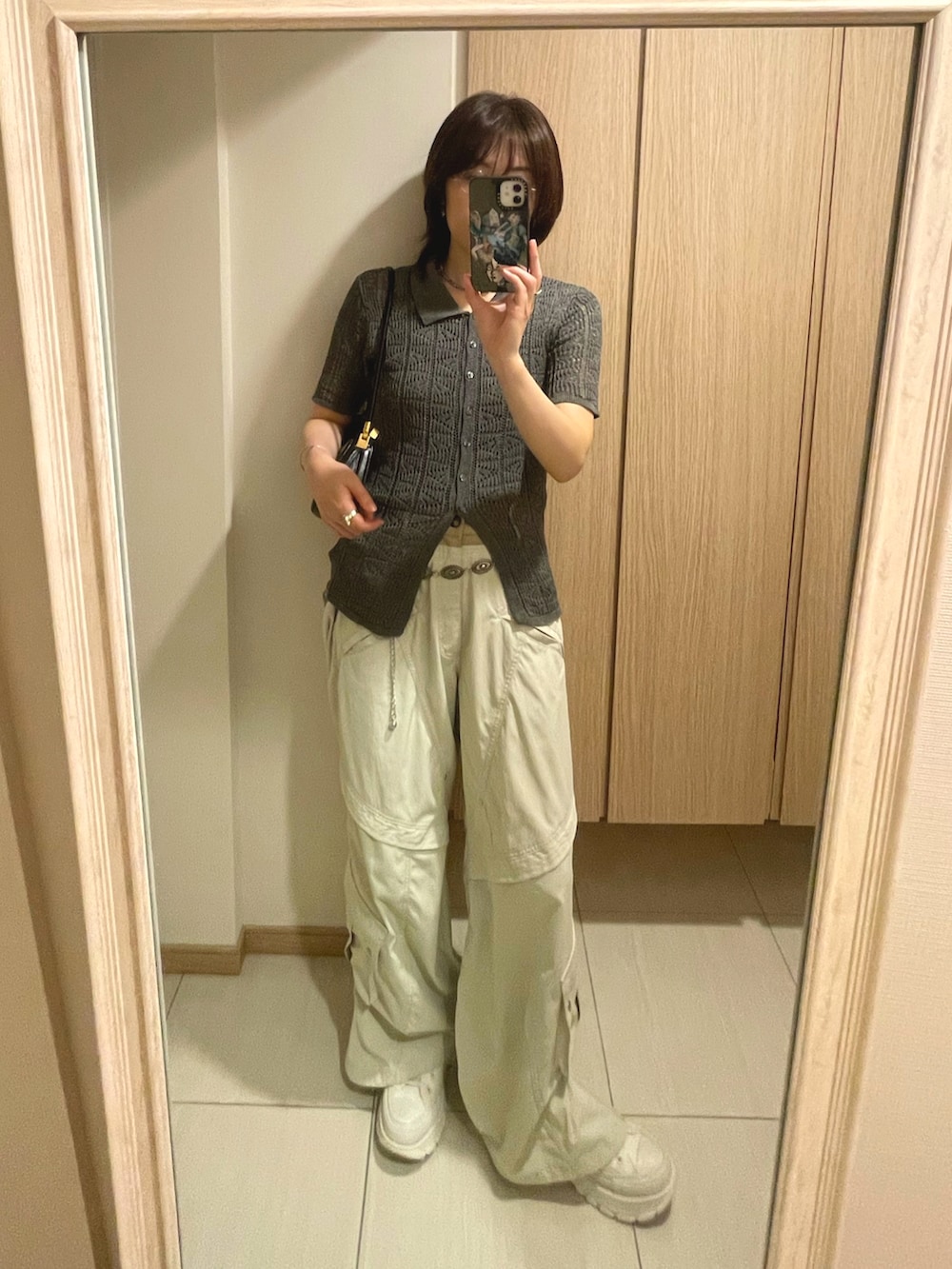 グレー系のニット/セーター、ホワイト系のカーゴパンツ、ブラック系のハンドバッグを着用したレディースの秋コーディネートの2枚目の写真
