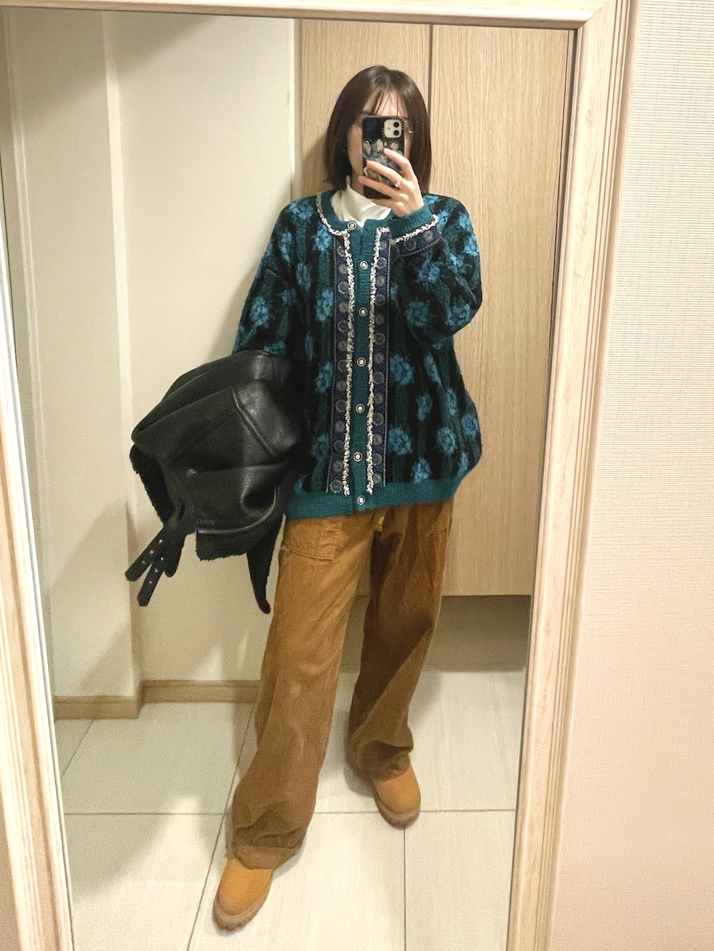 グリーン系のカーディガン/ボレロ、ブラック系のジャケット/アウターを着用したレディースの冬コーディネートの2枚目の写真