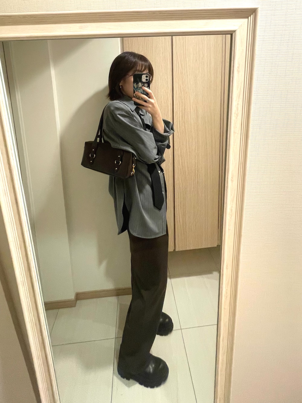 ブラック系のネクタイ、グレー系のシャツ/ブラウス、ブラウン系のスラックスを着用したレディースの秋コーディネートの2枚目の写真