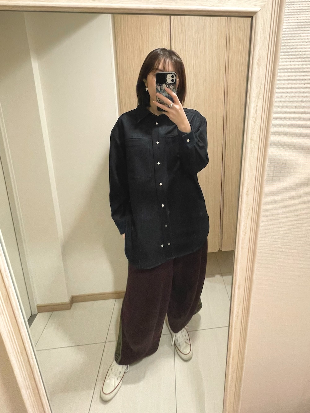 ブラック系のショルダーバッグ、ホワイト系のスニーカー、ブルー系のトップスを着用したレディースの秋コーディネートの3枚目の写真