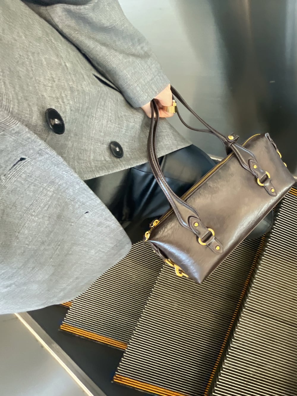 ブラック系のスラックス、グレー系のジャケット/アウター、シルバー系のピアス（両耳用）を着用したレディースの春コーディネートの3枚目の写真