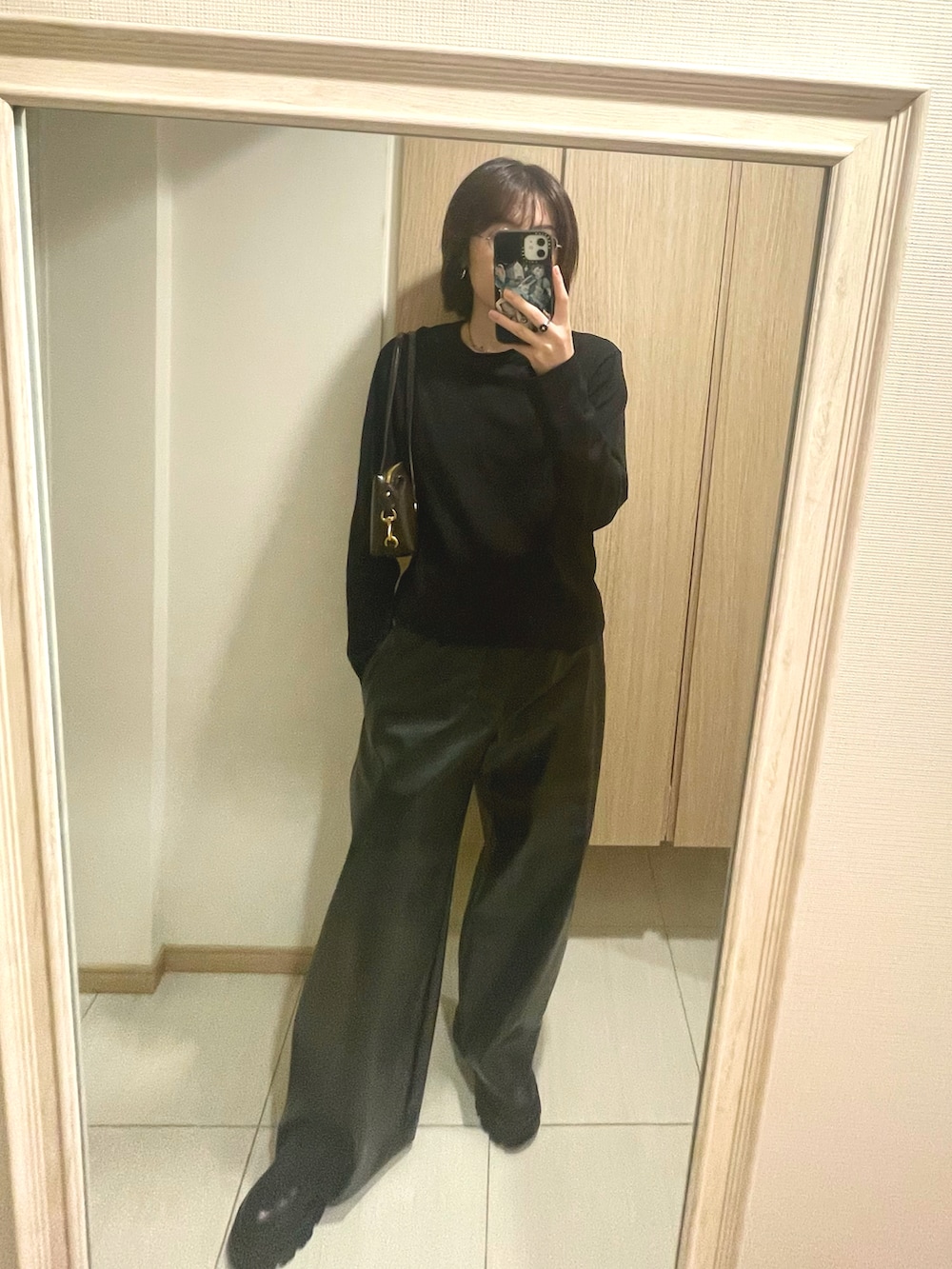 ブラック系のTシャツ/カットソー、ブラウン系のバッグ、ブラック系のパンツを着用したレディースの秋コーディネートの2枚目の写真