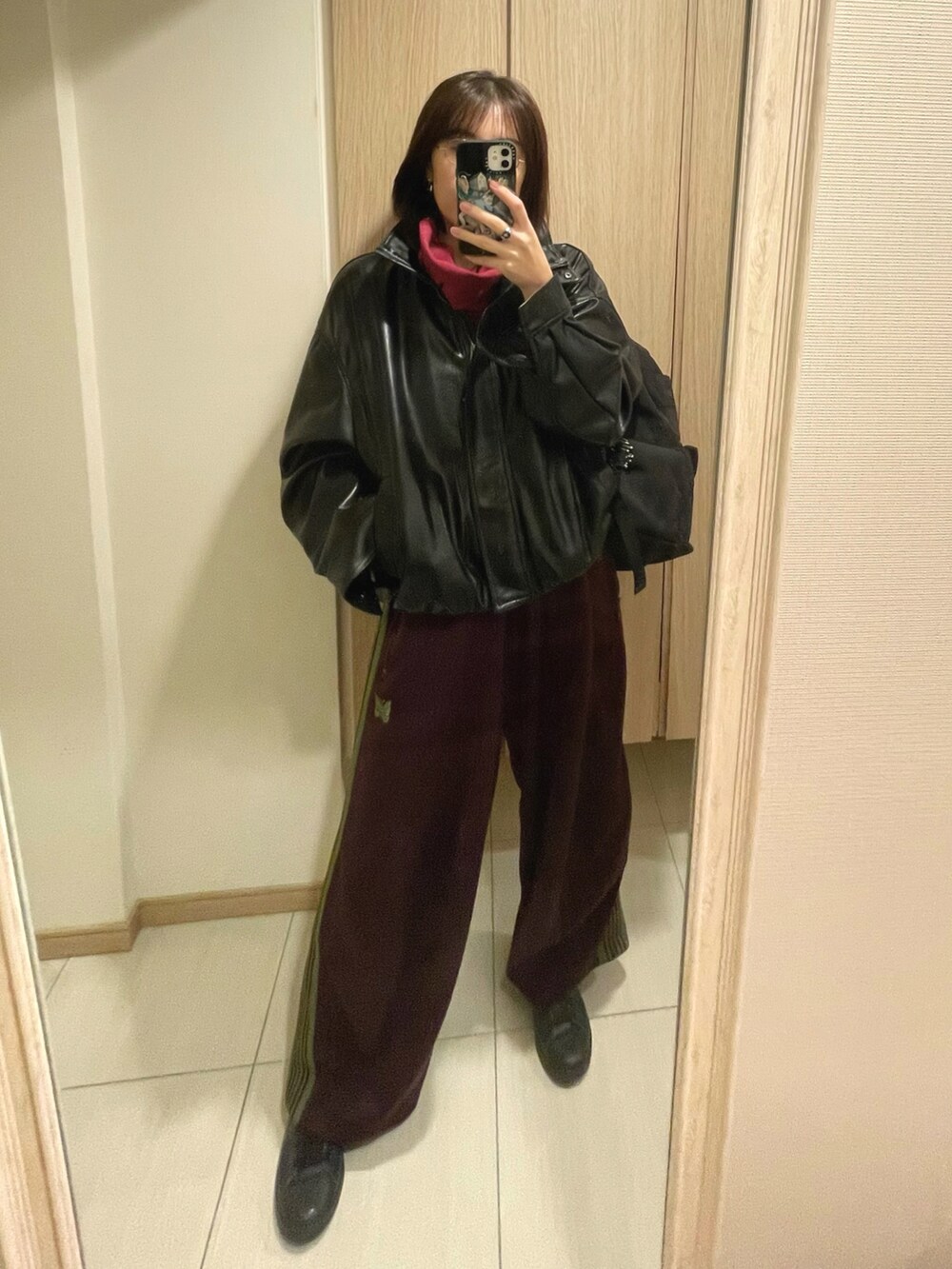 ブラック系のスニーカー、レッド系のトップス、ブラック系のブルゾンを着用したレディースの秋コーディネートの3枚目の写真