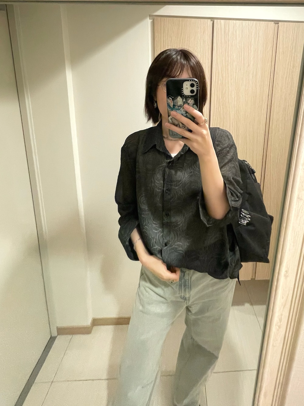 ブラック系のシャツ/ブラウス、ブルー系のデニムパンツを着用したレディースの秋コーディネートの2枚目の写真