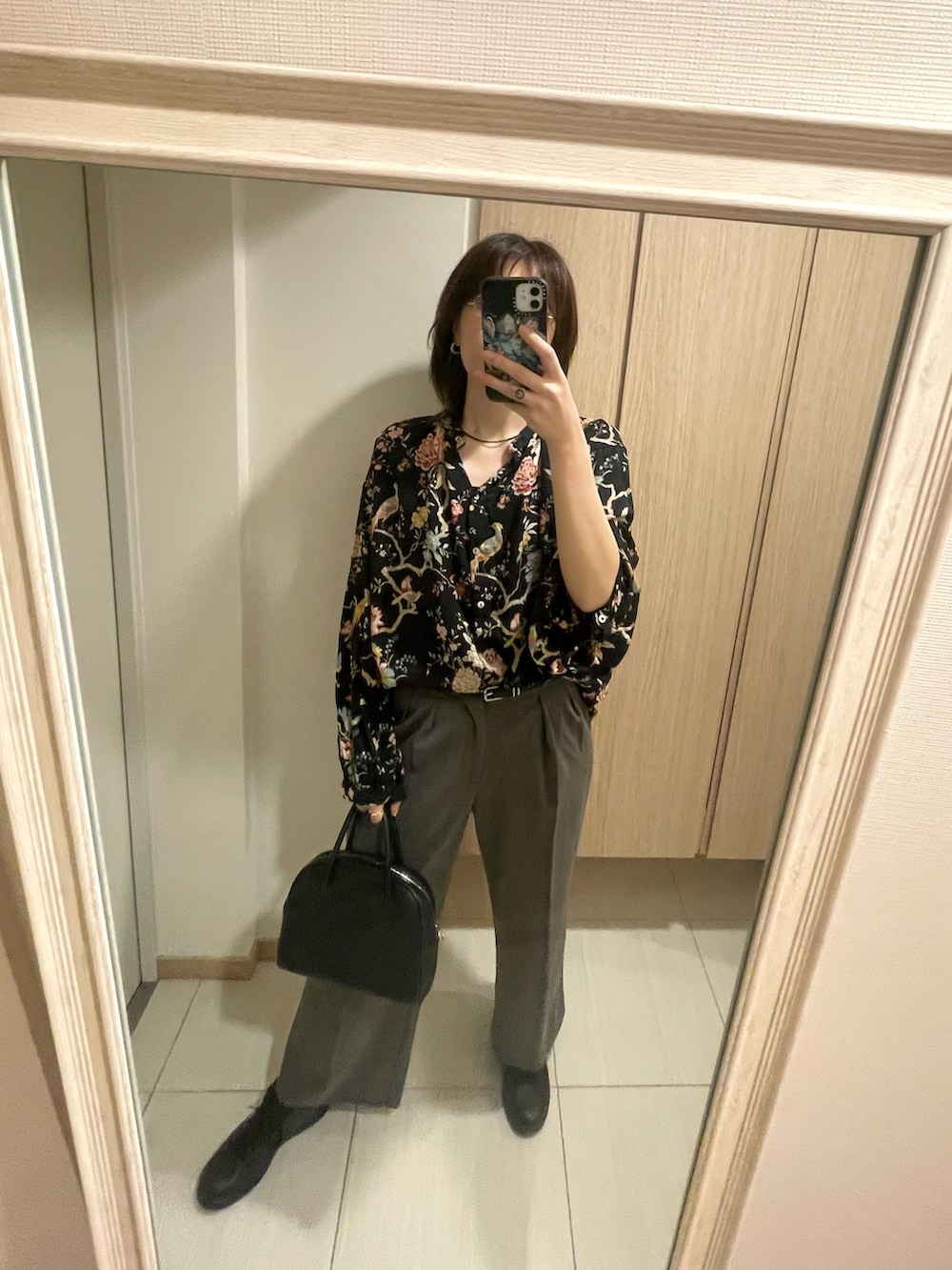 ブラック系のシャツ/ブラウス、ブラック系のハンドバッグ、ブラック系のスニーカーを着用したレディースの秋コーディネートの2枚目の写真