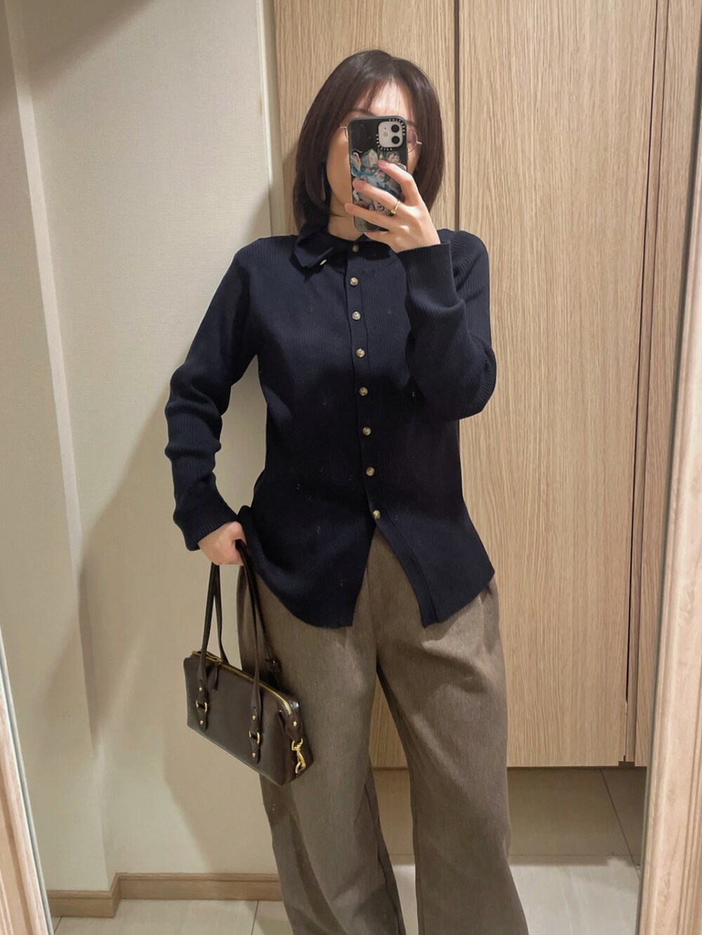 ブルー系のカーディガン/ボレロ、ブラウン系のパンツ、ブラウン系のバッグを着用したレディースの冬コーディネートの2枚目の写真