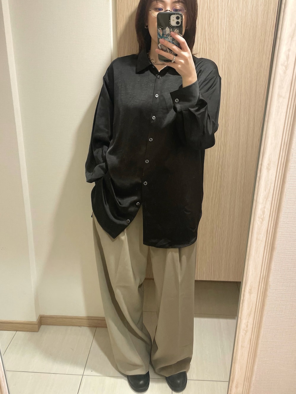 ブラック系のシャツ/ブラウス、ベージュ系のスラックス、ブラック系のブーツを着用したレディースの春コーディネートの2枚目の写真