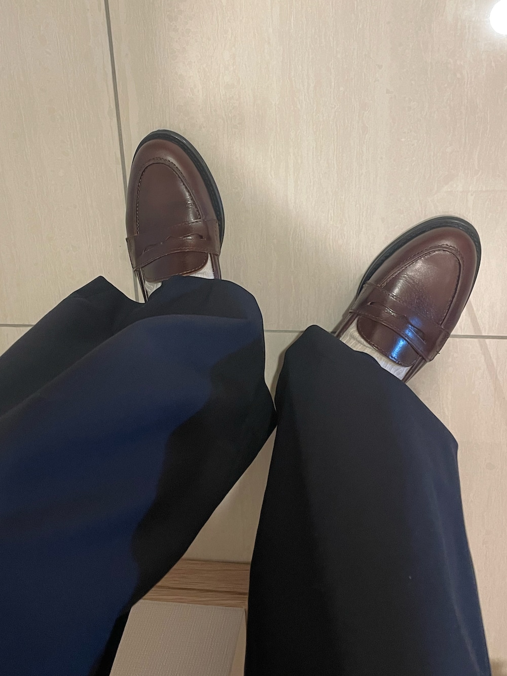 ブラック系のポロシャツ、ベージュ系のカーディガン/ボレロ、ブルー系のパンツを着用したレディースの春コーディネートの2枚目の写真