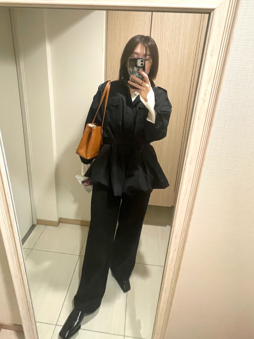 ブラック系のトレンチコート、イエロー系のハンドバッグを着用したレディースの春コーディネートの2枚目の写真