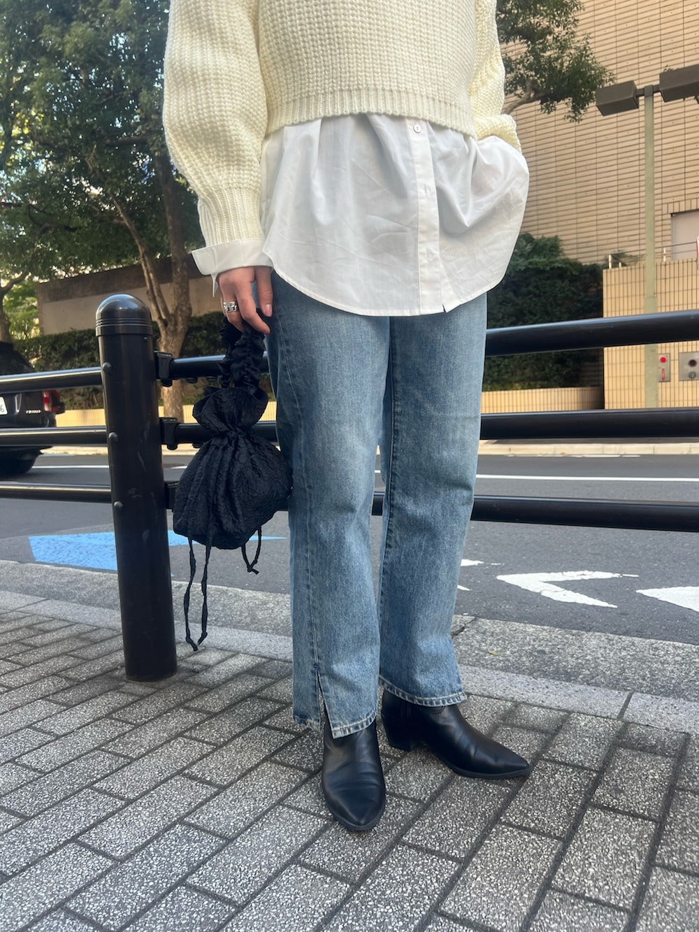 オレンジ系のチェスターコート、ホワイト系のニット/セーター、ブルー系のデニムパンツを着用したレディースの秋コーディネートの4枚目の写真