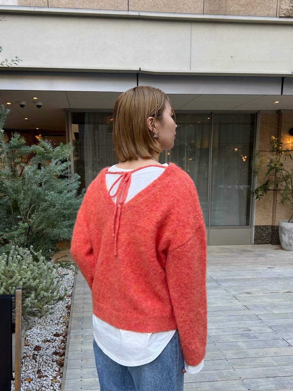 オレンジ系のニット/セーター、ホワイト系のTシャツ/カットソー、ブルー系のデニムパンツを着用したレディースの冬コーディネートの3枚目の写真