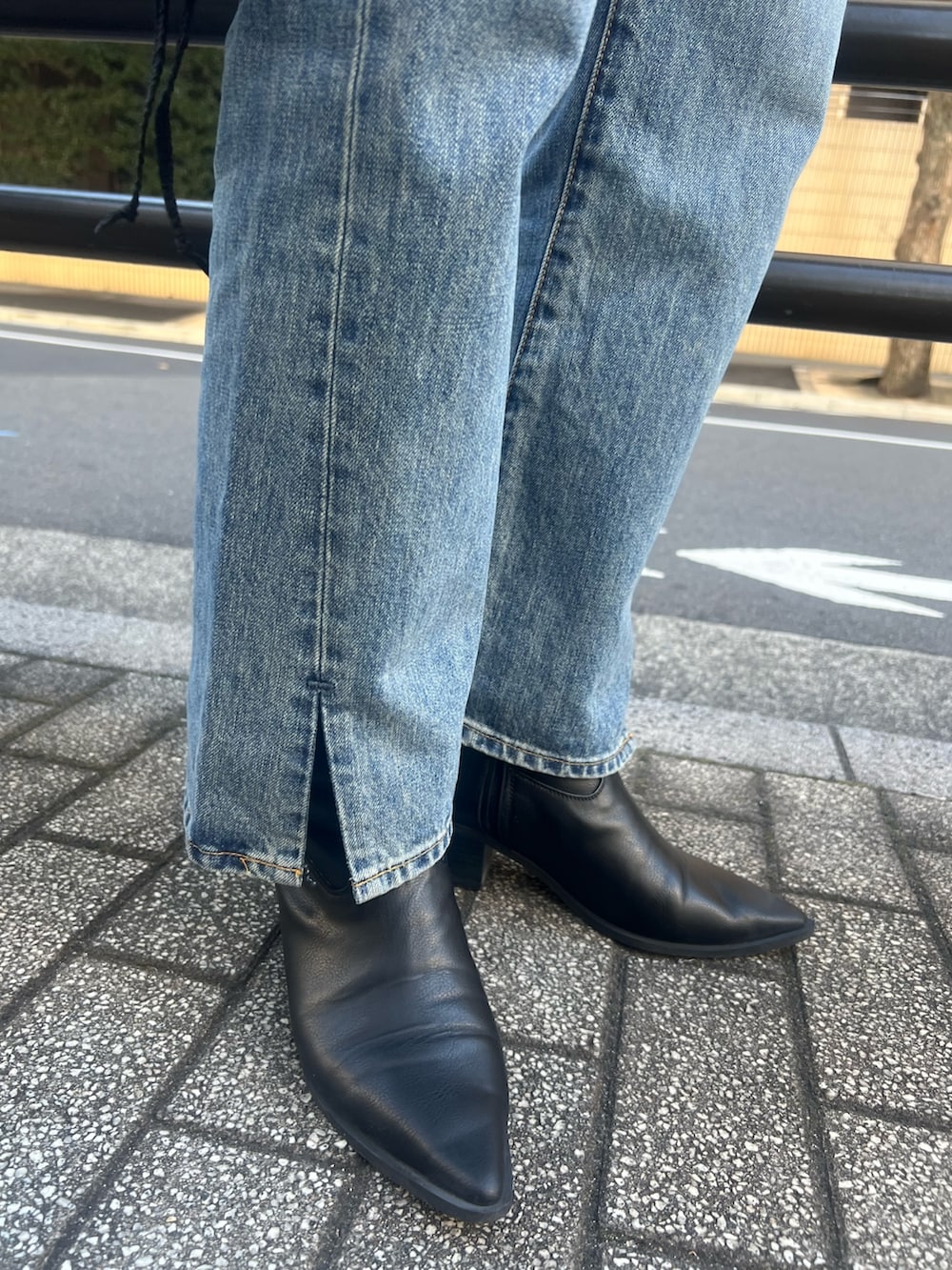 オレンジ系のチェスターコート、ホワイト系のニット/セーター、ブルー系のデニムパンツを着用したレディースの秋コーディネートの5枚目の写真