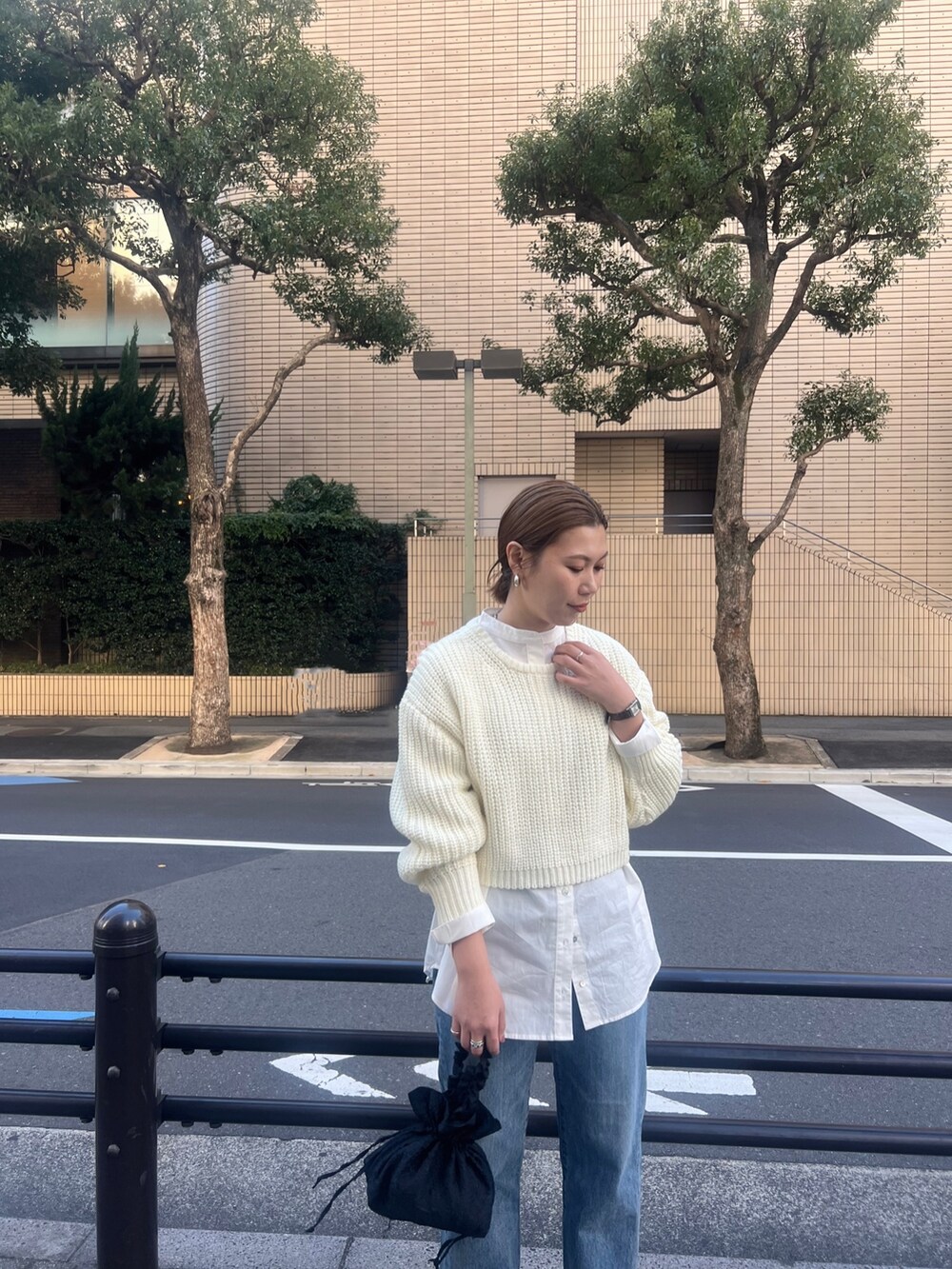 オレンジ系のチェスターコート、ホワイト系のニット/セーター、ブルー系のデニムパンツを着用したレディースの秋コーディネートの3枚目の写真