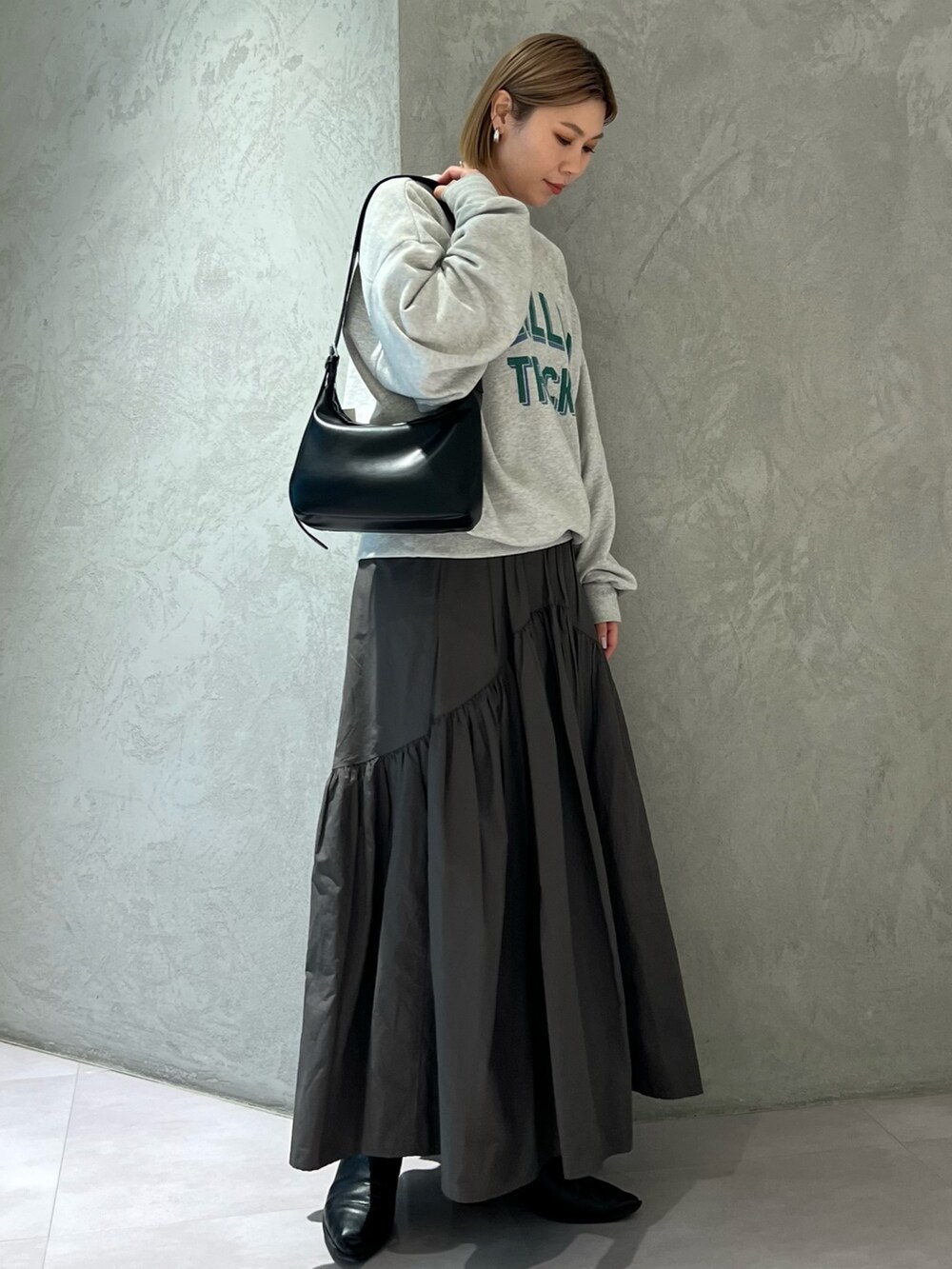 グレー系のスウェット、グレー系のスカート、ブラック系のショルダーバッグを着用したレディースの春コーディネートの3枚目の写真
