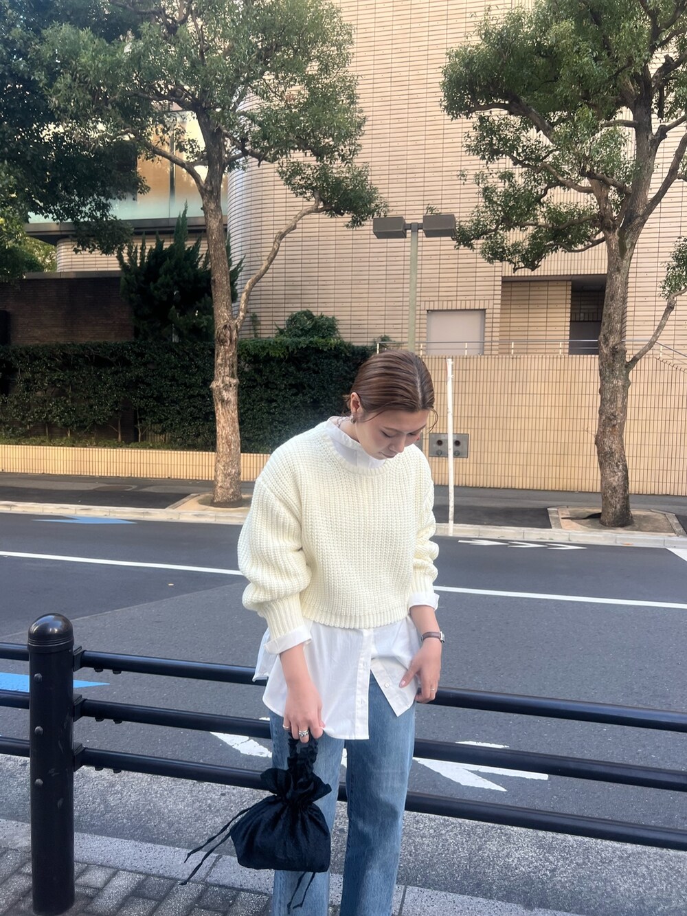 オレンジ系のチェスターコート、ホワイト系のニット/セーター、ブルー系のデニムパンツを着用したレディースの秋コーディネートの7枚目の写真