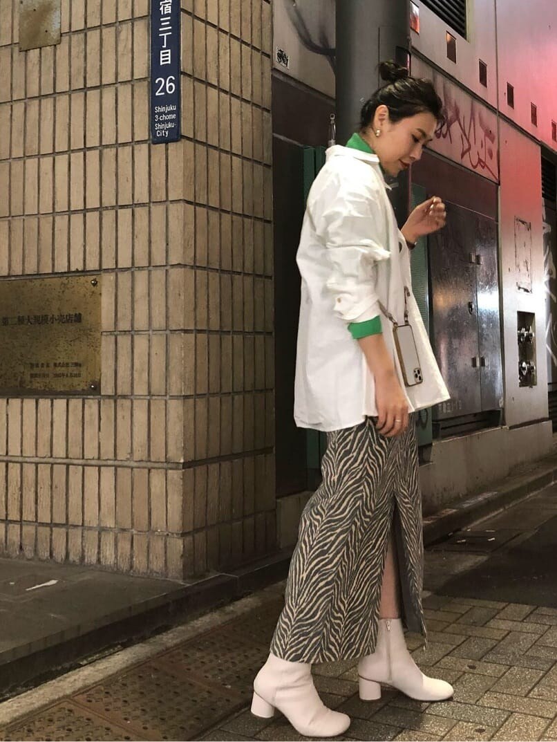 グリーン系のニット/セーター、ブルー系のスカート、ホワイト系のシャツ/ブラウスを着用したレディースの秋コーディネートの2枚目の写真