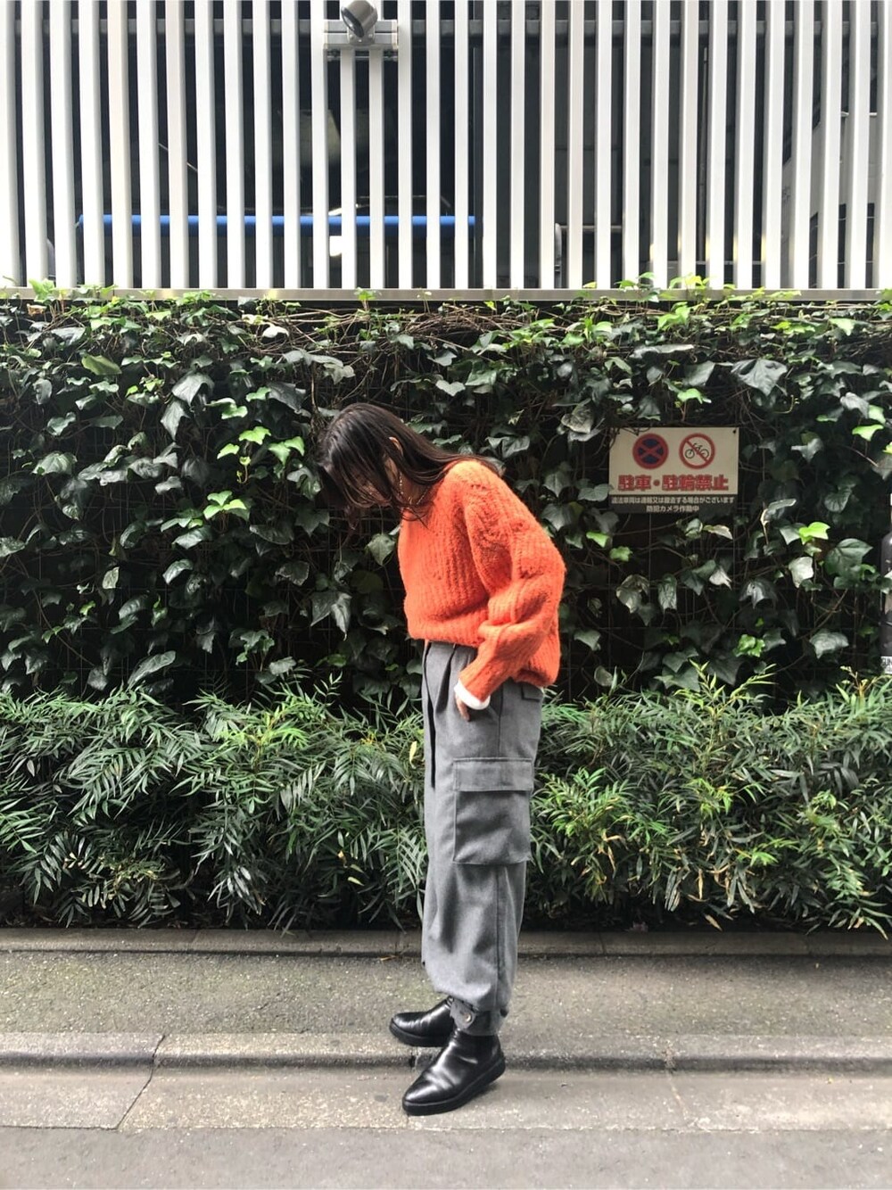 ホワイト系のTシャツ/カットソー、グレー系のカーゴパンツ、オレンジ系のニット/セーターを着用したレディースの秋コーディネートの2枚目の写真