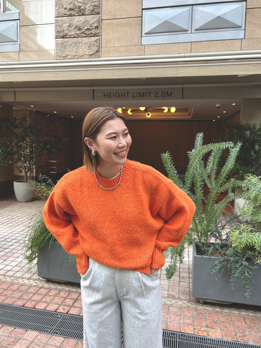 その他のチェスターコート、オレンジ系のニット/セーター、グレー系のその他パンツを着用したレディースの冬コーディネートの5枚目の写真