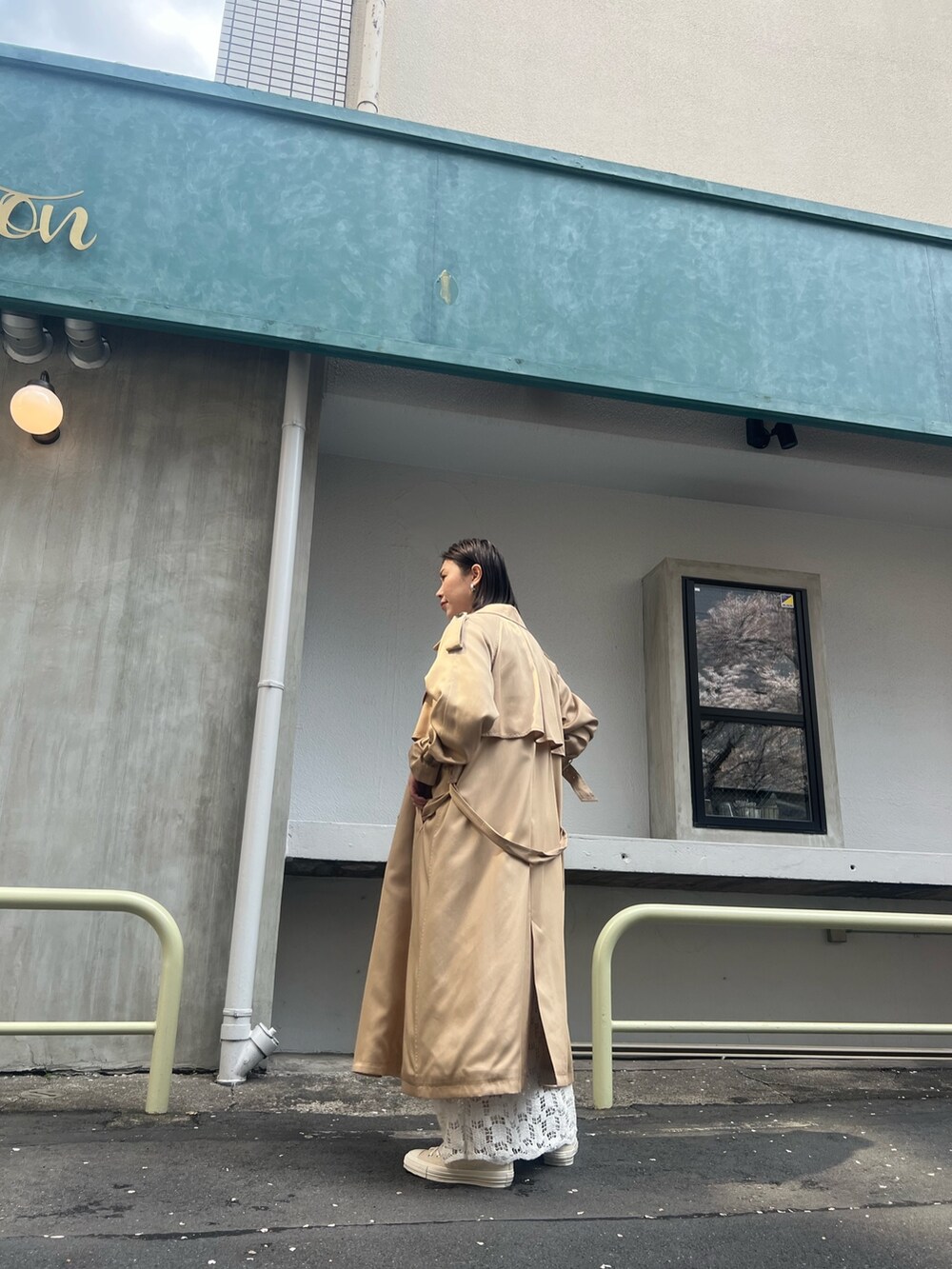 ベージュ系のトレンチコート、ホワイト系のTシャツ/カットソー、ホワイト系のスカートを着用したレディースの春コーディネートの3枚目の写真