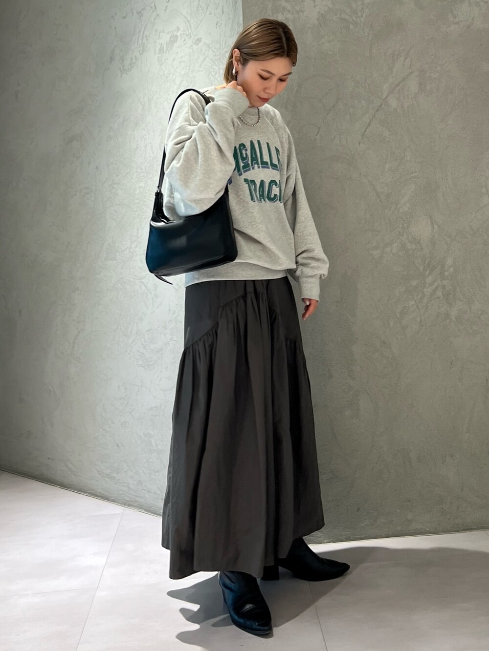 グレー系のスウェット、グレー系のスカート、ブラック系のショルダーバッグを着用したレディースの春コーディネートの2枚目の写真