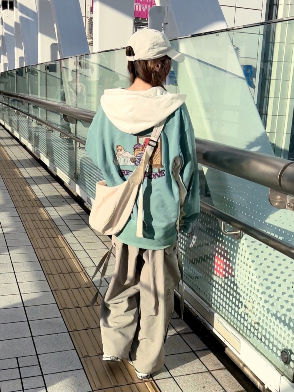 グリーン系のパーカー、グレー系のカーゴパンツ、ブラック系のスニーカーを着用したレディースの秋コーディネートの2枚目の写真