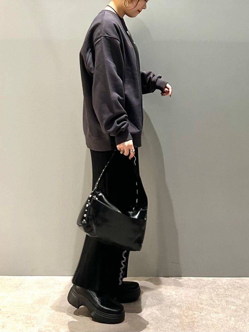 ブラック系のブーツ、ブラック系のハンドバッグ、グレー系のスウェットを着用したレディースの冬コーディネートの2枚目の写真