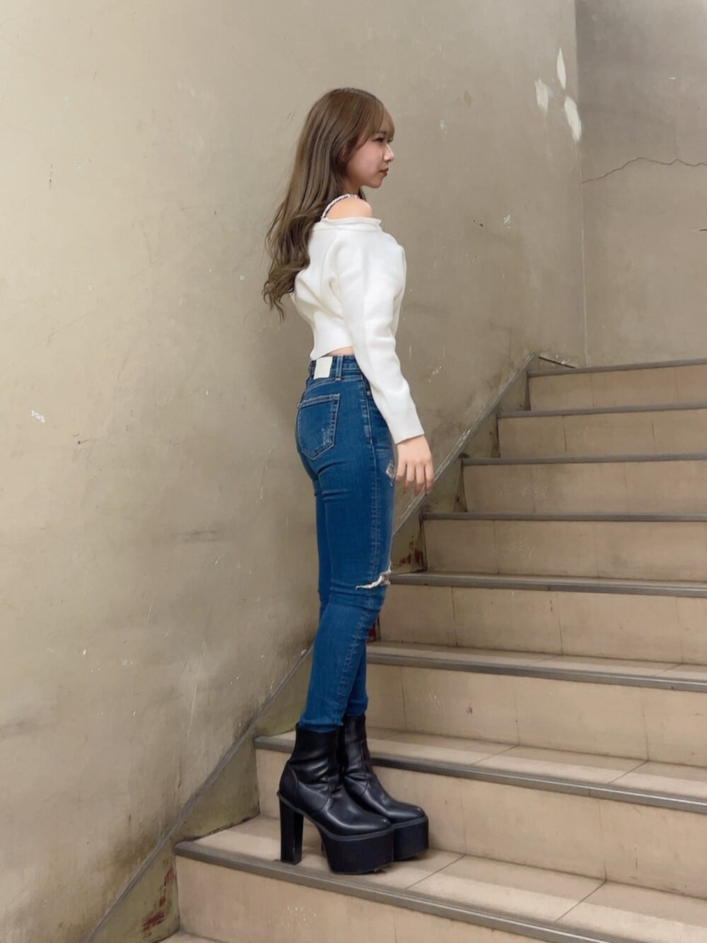 ブルー系のデニムパンツ、ホワイト系のニット/セーター、ブラック系のブーツを着用したレディースの秋コーディネートの4枚目の写真