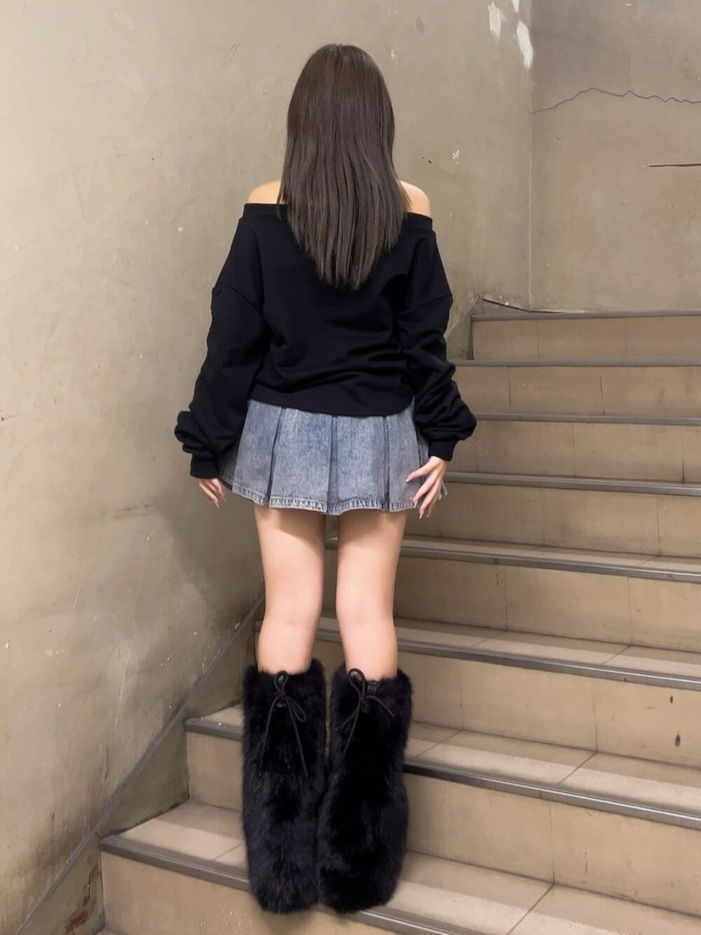 ブルー系のデニムスカート、ブラック系のスウェット、ブラック系のブーツを着用したレディースの冬コーディネートの3枚目の写真