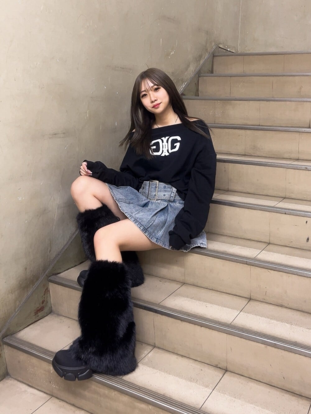 ブルー系のデニムスカート、ブラック系のスウェット、ブラック系のブーツを着用したレディースの冬コーディネートの4枚目の写真