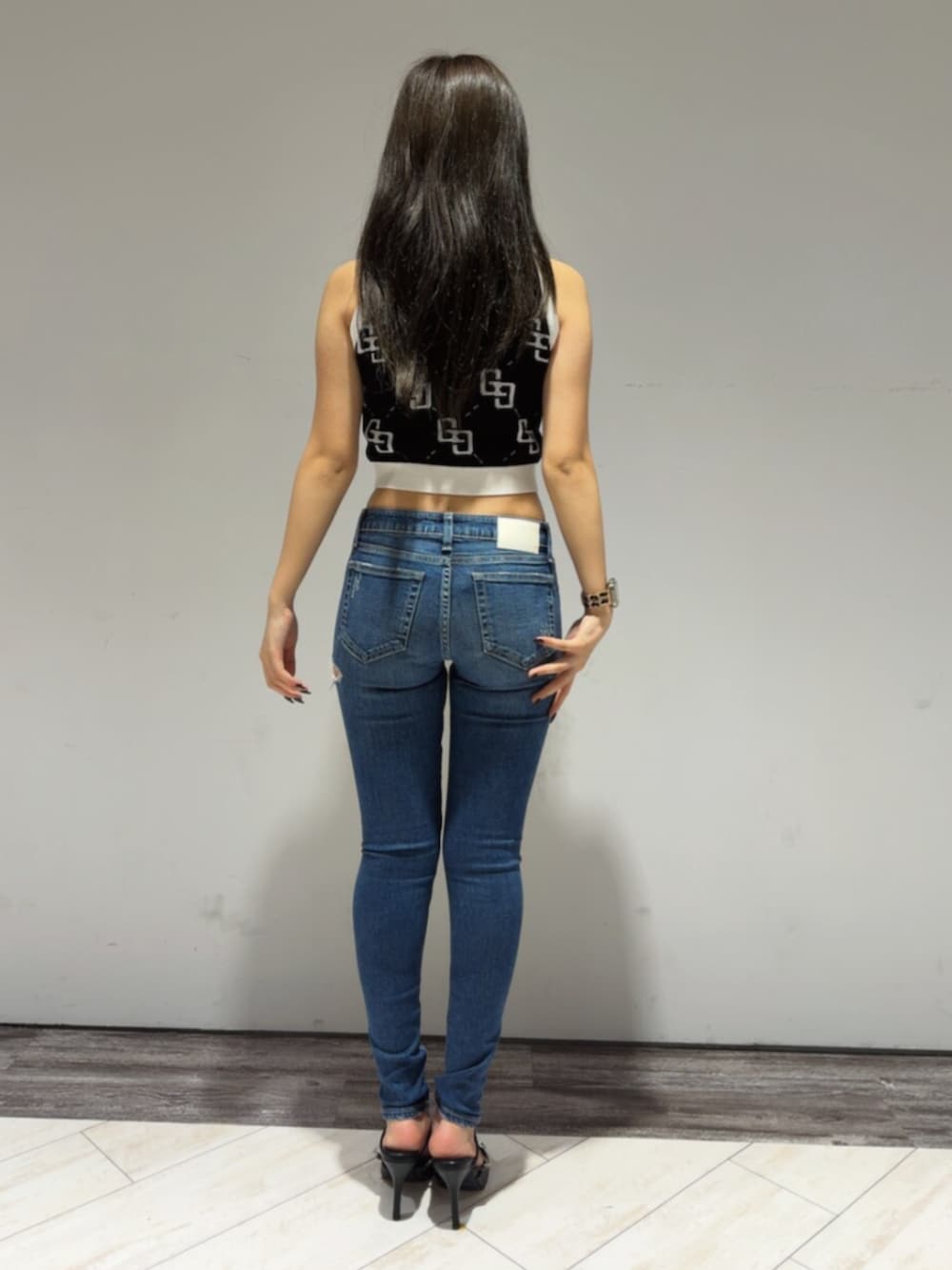 ブラック系のタンクトップ、ブルー系のデニムパンツ、ブラック系のパンプスを着用したレディースの春コーディネートの4枚目の写真