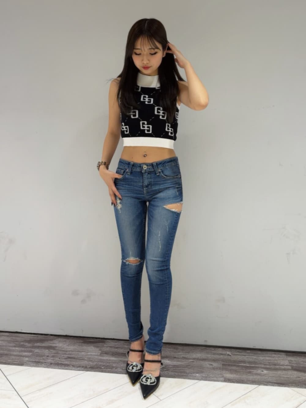 ブラック系のタンクトップ、ブルー系のデニムパンツ、ブラック系のパンプスを着用したレディースの春コーディネートの2枚目の写真