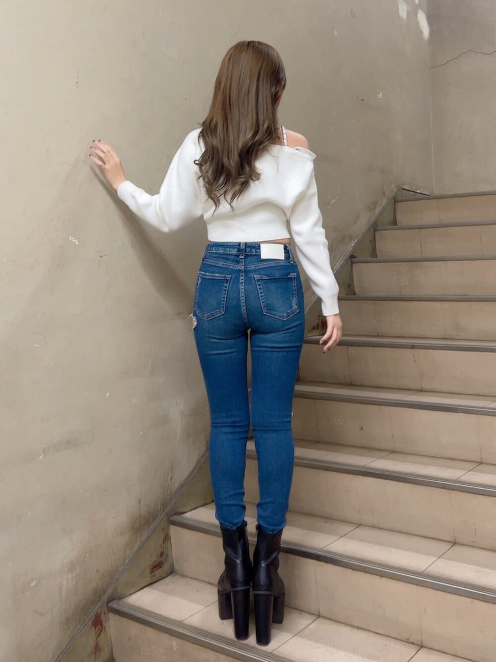 ブルー系のデニムパンツ、ホワイト系のニット/セーター、ブラック系のブーツを着用したレディースの秋コーディネートの3枚目の写真