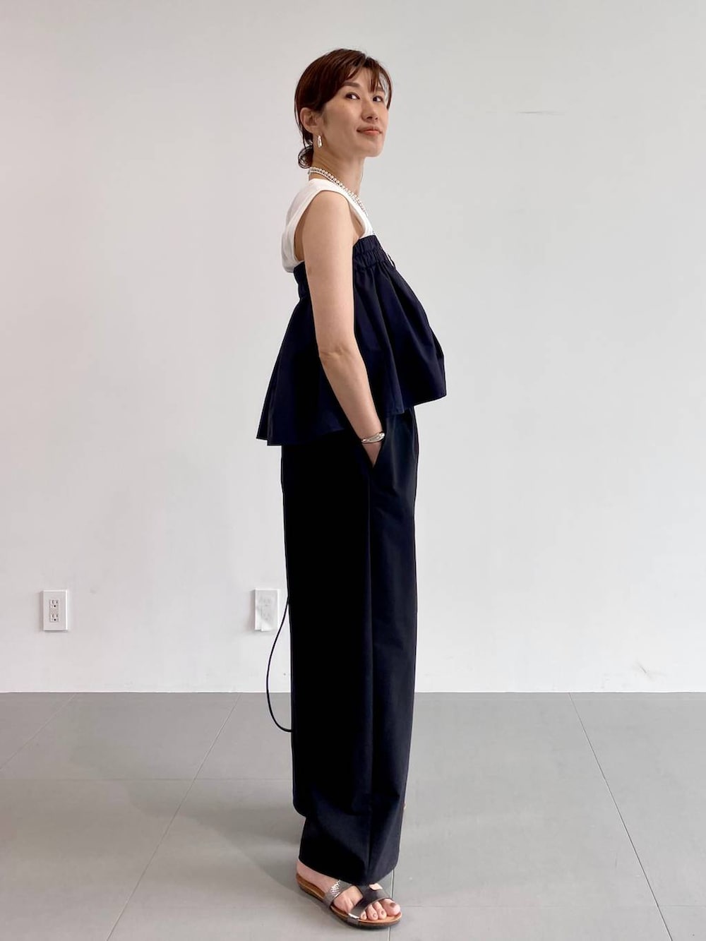 シルバー系のサンダル、ブラック系のショルダーバッグ、ホワイト系のTシャツ/カットソーを着用したレディースの夏コーディネートの3枚目の写真