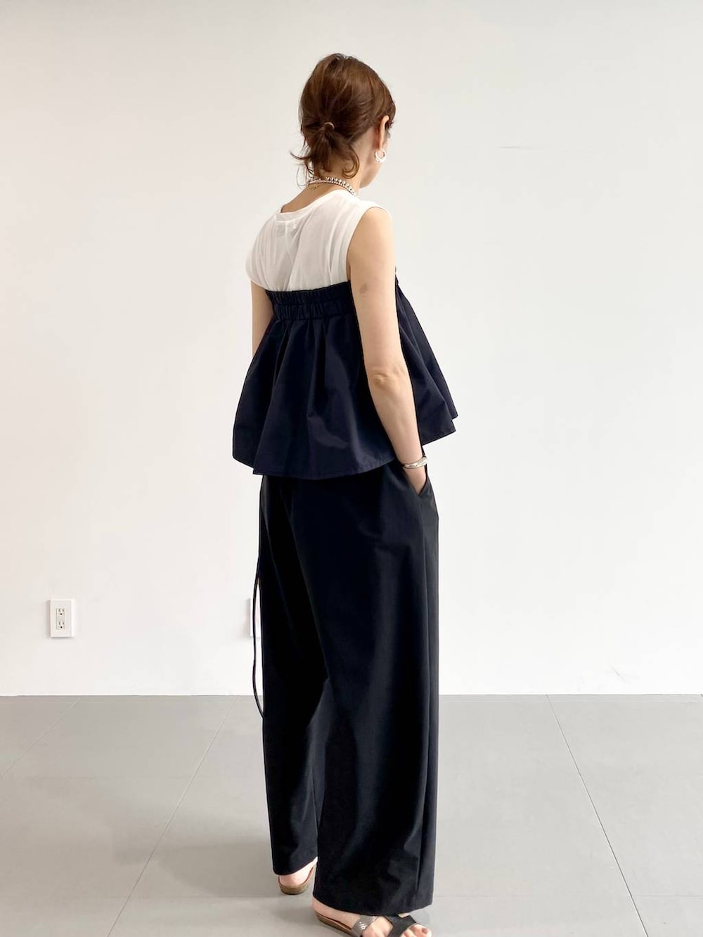 シルバー系のサンダル、ブラック系のショルダーバッグ、ホワイト系のTシャツ/カットソーを着用したレディースの夏コーディネートの2枚目の写真