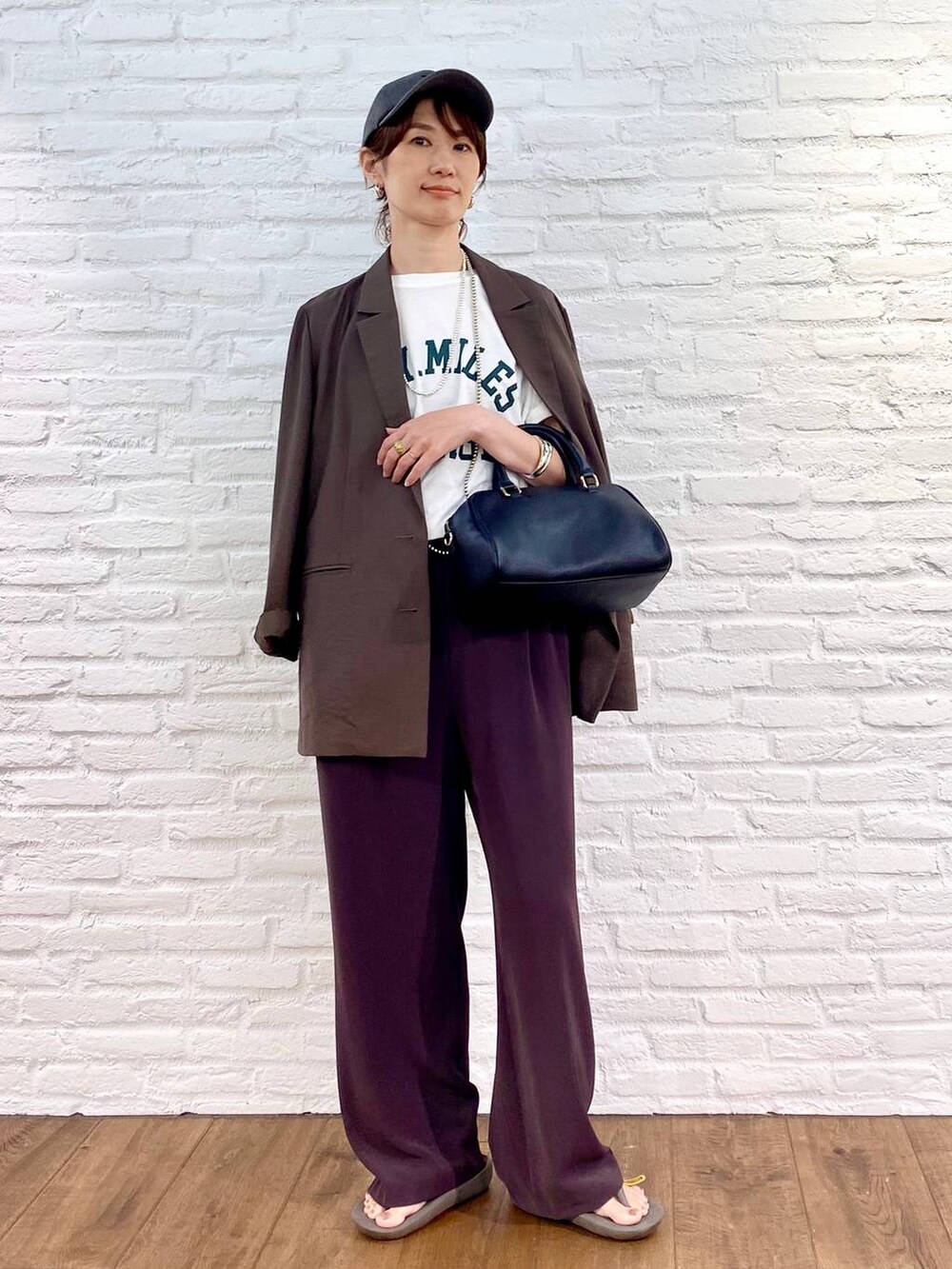 ブラック系のボストンバッグ、ブラウン系のスラックス、ホワイト系のTシャツ/カットソーを着用したレディースの夏コーディネートの4枚目の写真