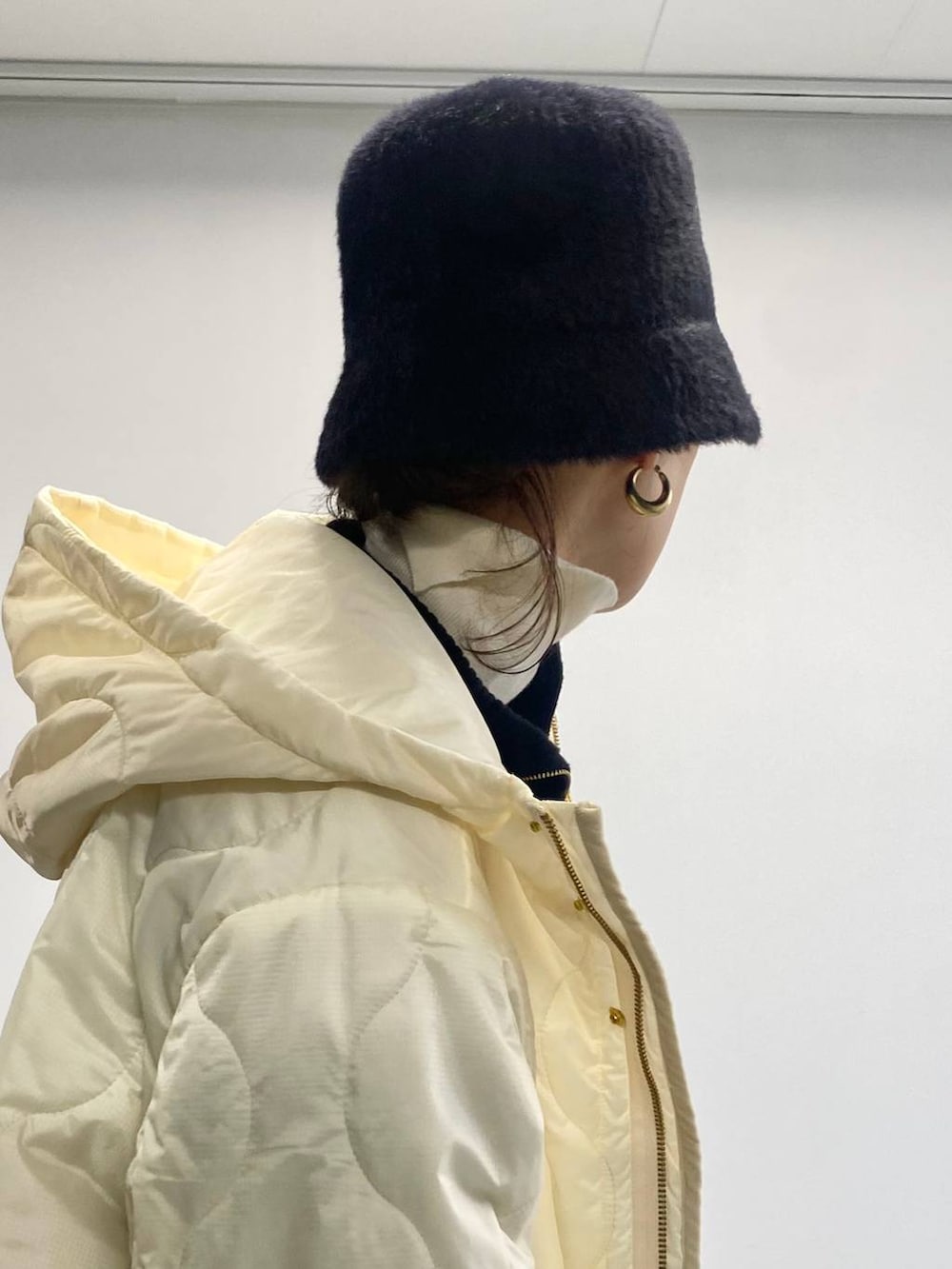 ホワイト系のニット/セーター、ホワイト系のナイロンジャケット、ブラック系のハットを着用したレディースの冬コーディネートの2枚目の写真
