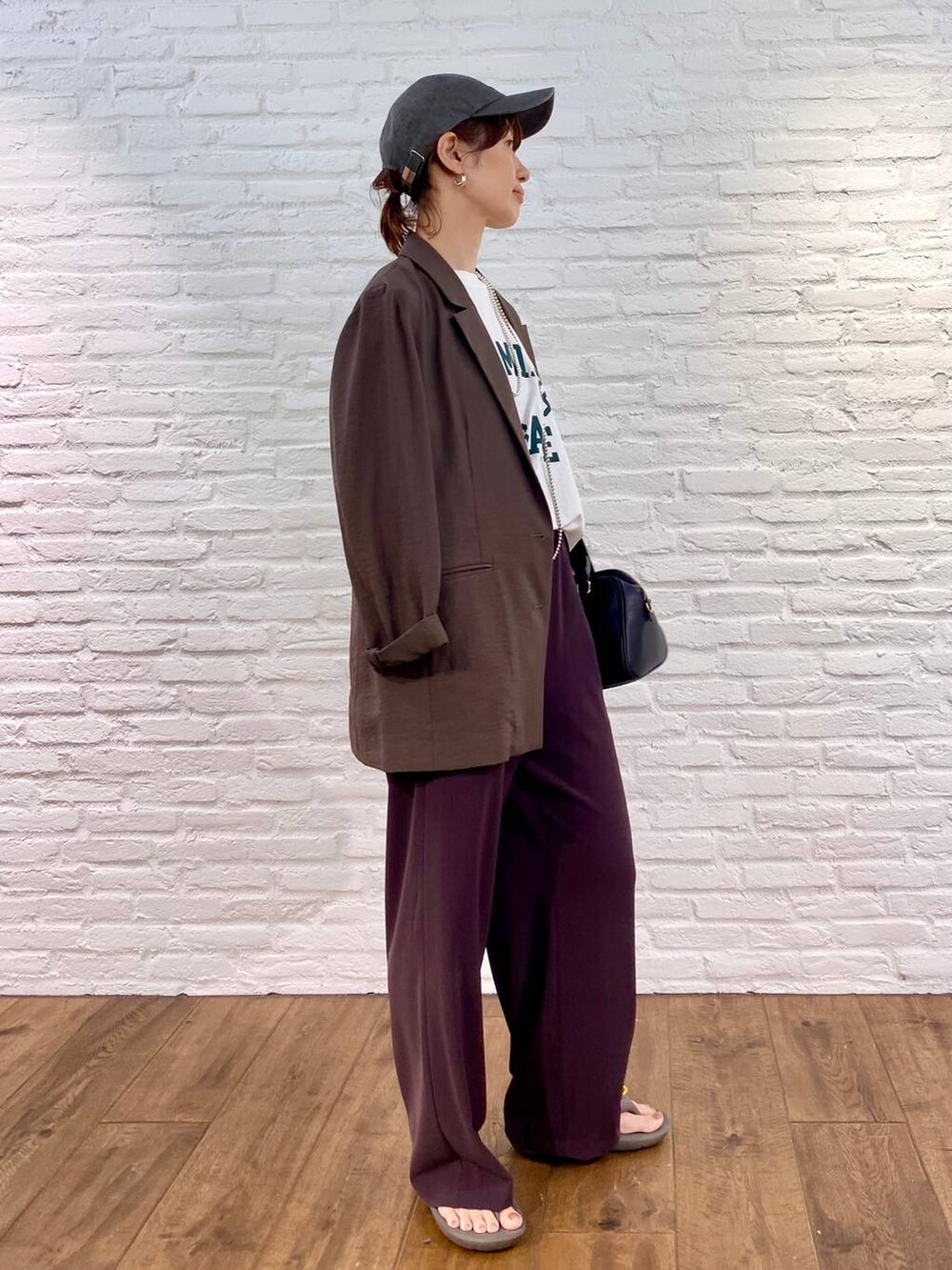 ブラック系のボストンバッグ、ブラウン系のスラックス、ホワイト系のTシャツ/カットソーを着用したレディースの夏コーディネートの2枚目の写真