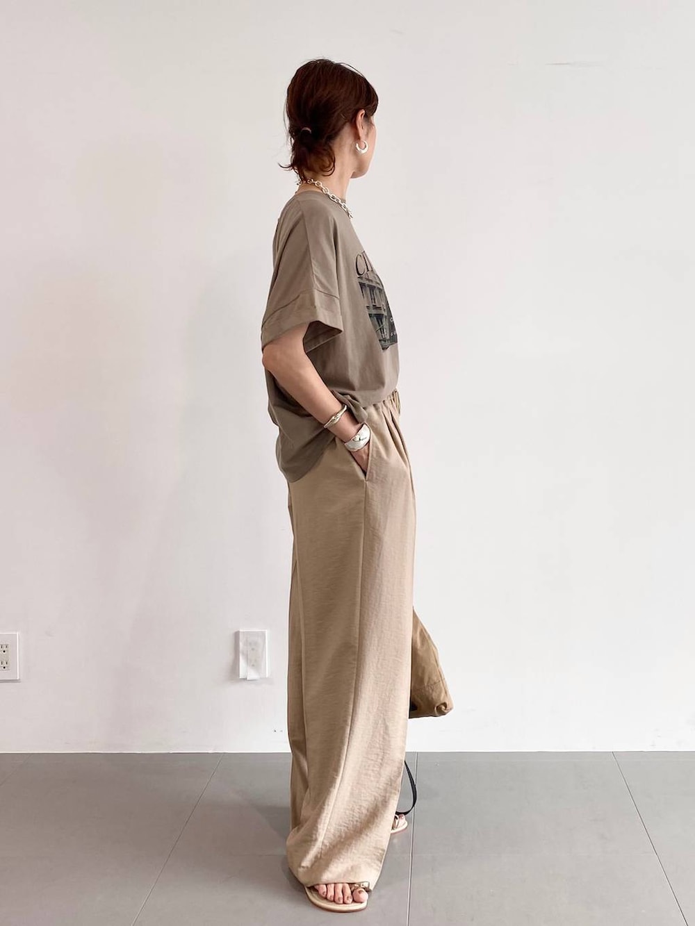 ブラウン系のバックパック/リュック、イエロー系のサンダル、ベージュ系のスラックスを着用したレディースの夏コーディネートの3枚目の写真