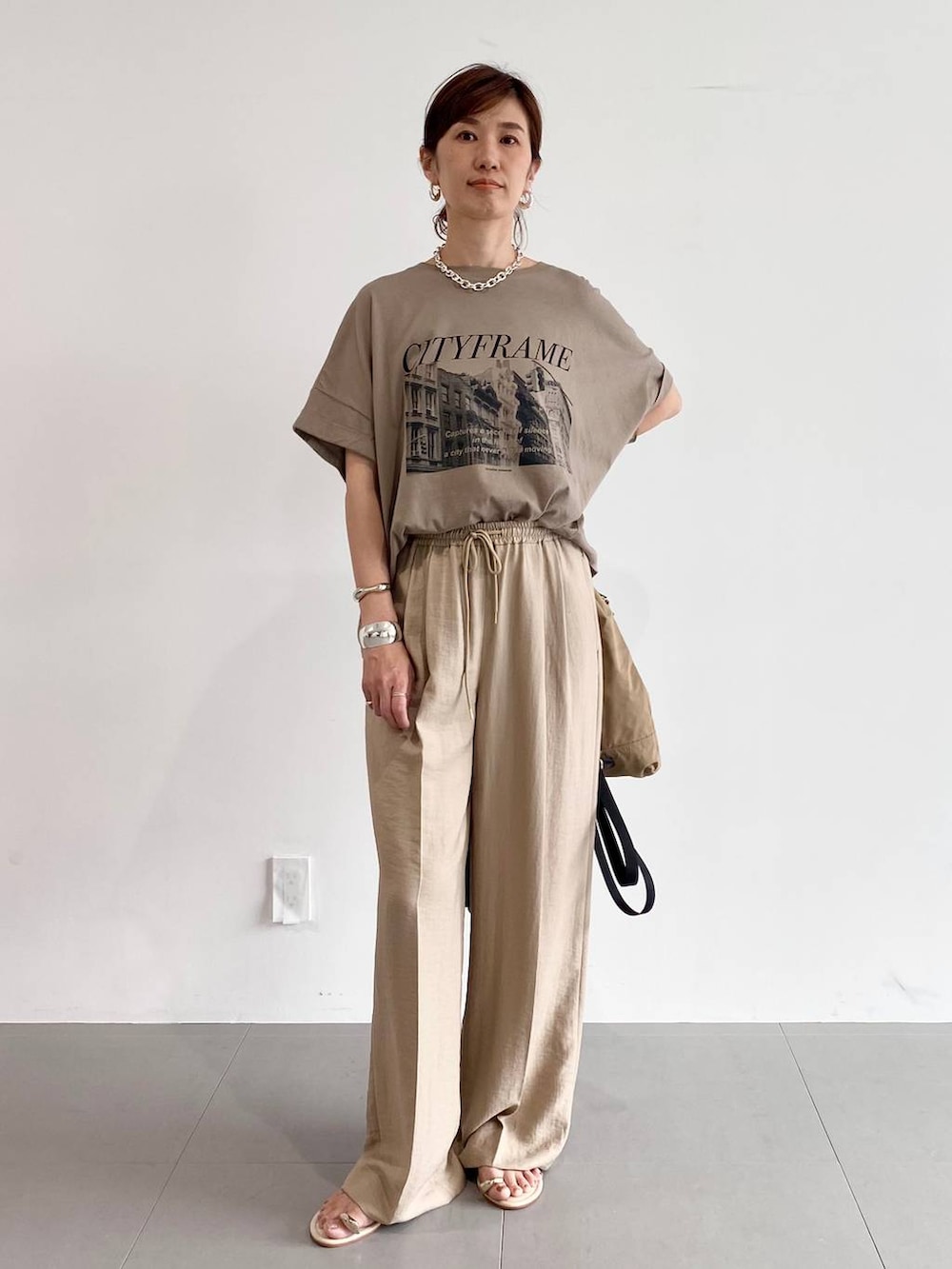 ブラウン系のバックパック/リュック、イエロー系のサンダル、ベージュ系のスラックスを着用したレディースの夏コーディネートの2枚目の写真