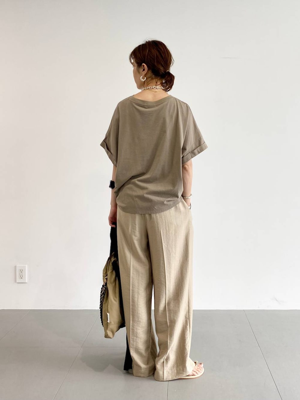 ブラウン系のバックパック/リュック、イエロー系のサンダル、ベージュ系のスラックスを着用したレディースの夏コーディネートの4枚目の写真