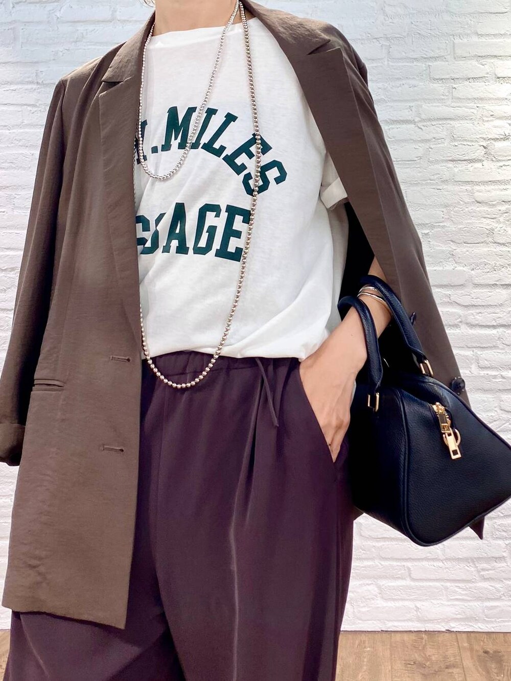 ブラック系のボストンバッグ、ブラウン系のスラックス、ホワイト系のTシャツ/カットソーを着用したレディースの夏コーディネートの5枚目の写真