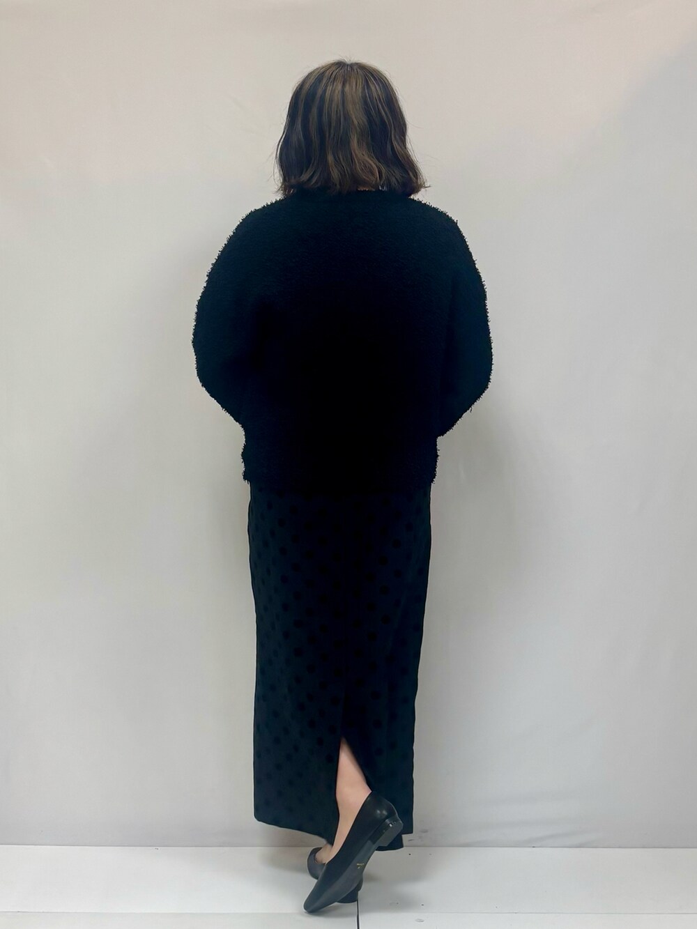 ブラック系のニット/セーター、グレー系のスカートを着用したレディースの春コーディネートの2枚目の写真