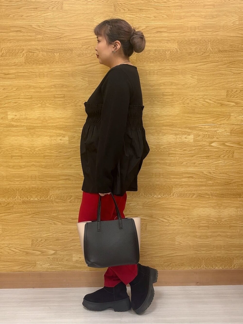 ブラック系のチュニック、レッド系のその他パンツ、ブラック系のブーツを着用したレディースの冬コーディネートの2枚目の写真