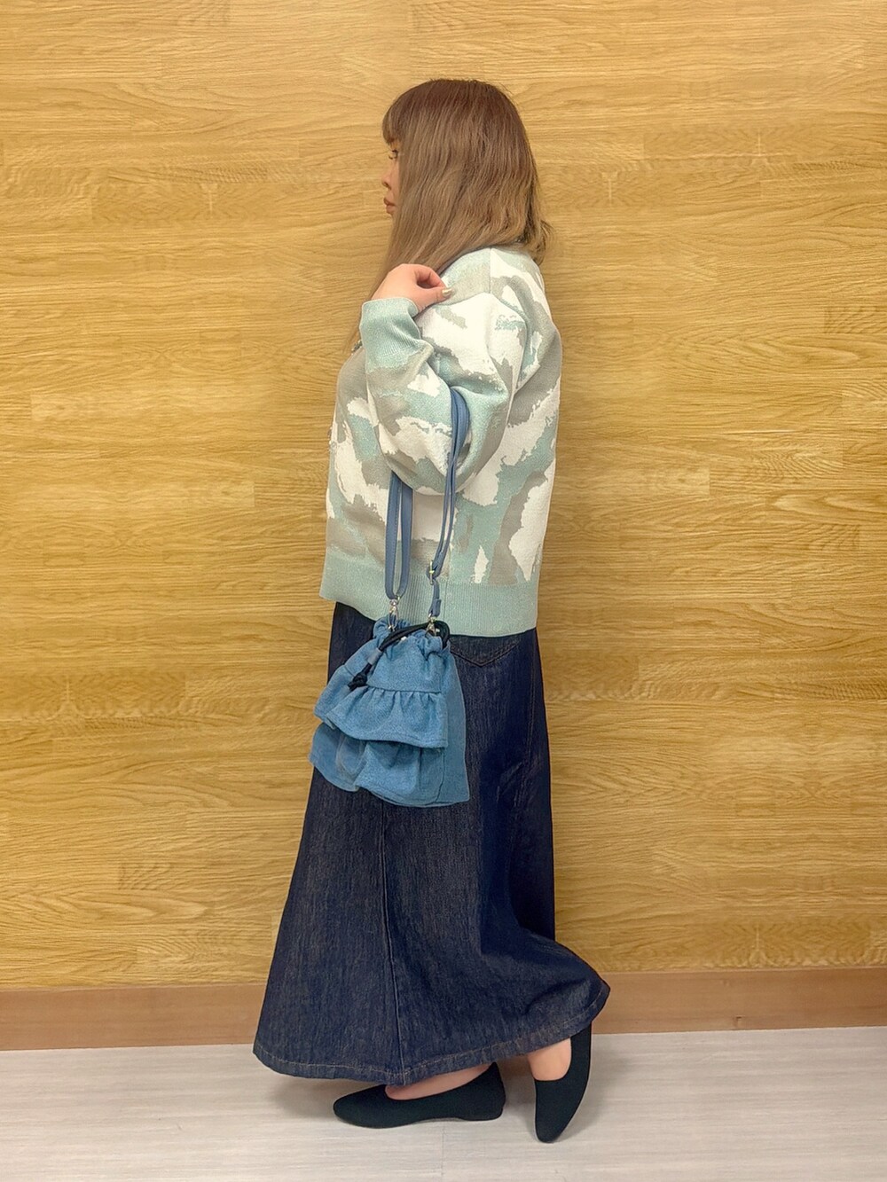ブルー系のデニムスカート、グリーン系のニット/セーターを着用したレディースの春コーディネートの2枚目の写真