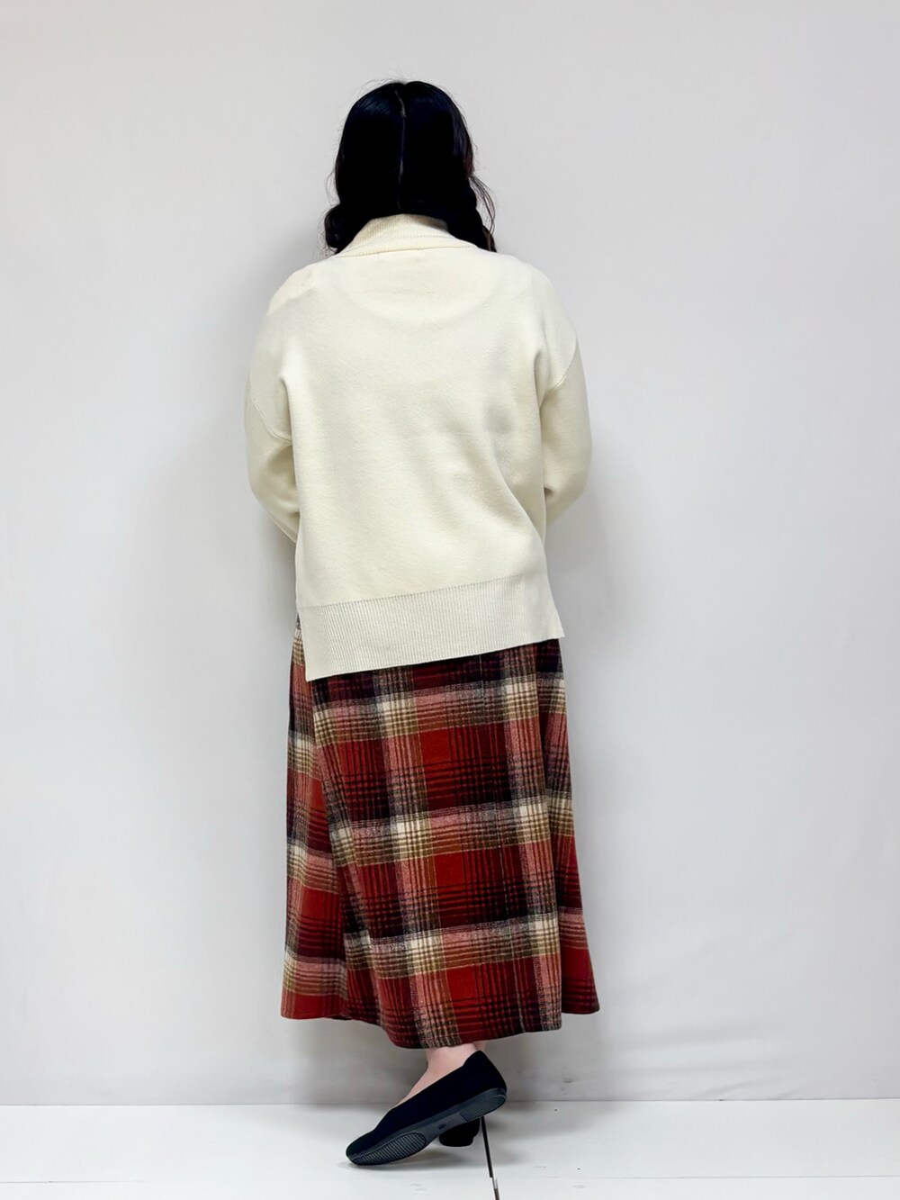 ベージュ系のスカート、ブラック系のパンプス、オレンジ系のニット/セーターを着用したレディースの冬コーディネートの3枚目の写真