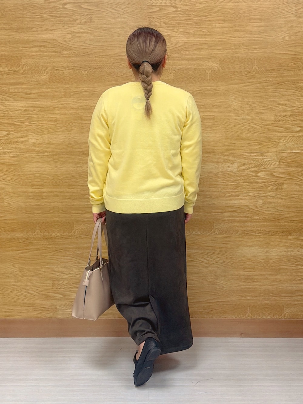 イエロー系のニット/セーター、イエロー系のカーディガン/ボレロ、グレー系のスカートを着用したレディースの冬コーディネートの2枚目の写真