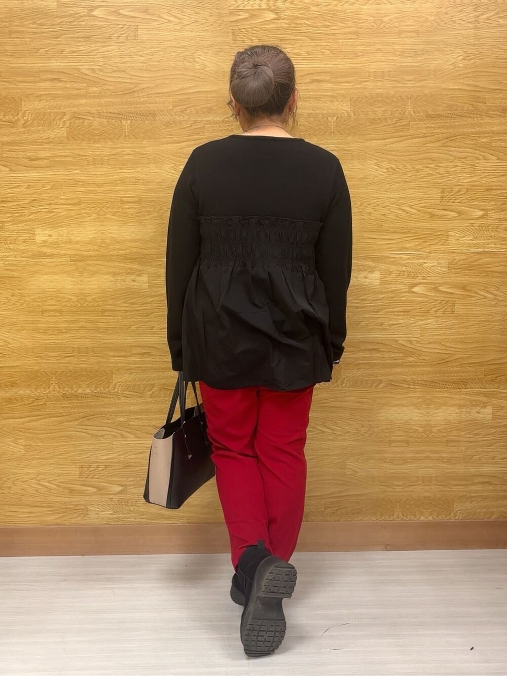 ブラック系のチュニック、レッド系のその他パンツ、ブラック系のブーツを着用したレディースの冬コーディネートの3枚目の写真