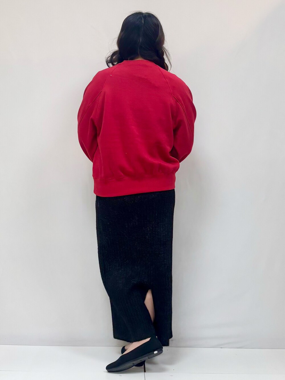 レッド系のTシャツ/カットソー、ブラック系のスカート、ブラック系のパンプスを着用したレディースの冬コーディネートの3枚目の写真